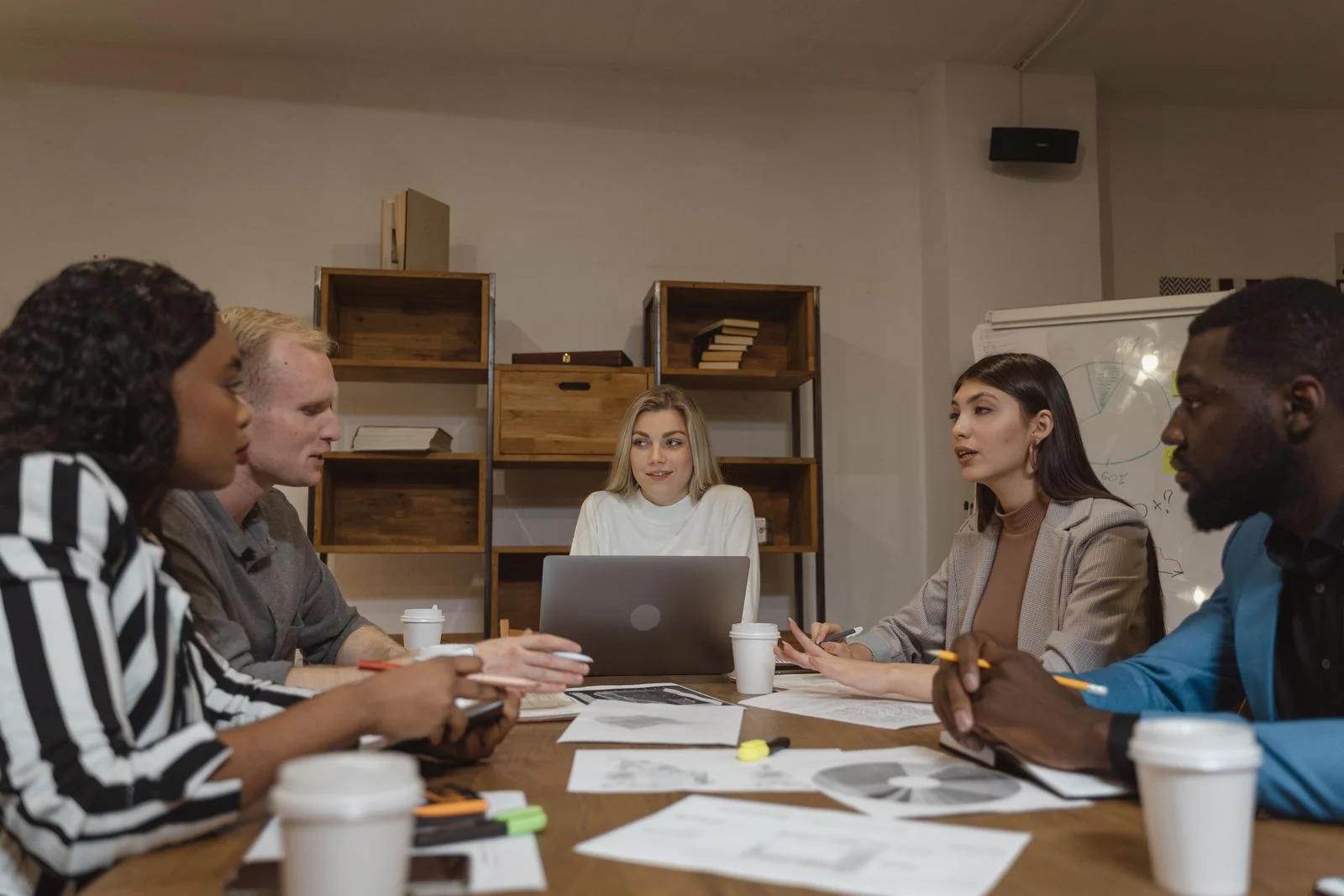 Five professionals in a conversation around a conference table