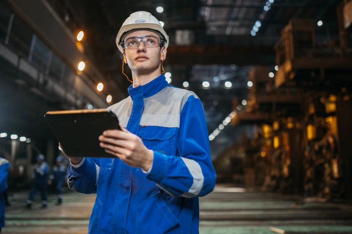 Engineer with a tablet on a metal factory floor